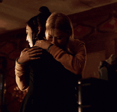 two women are hugging in a dark room