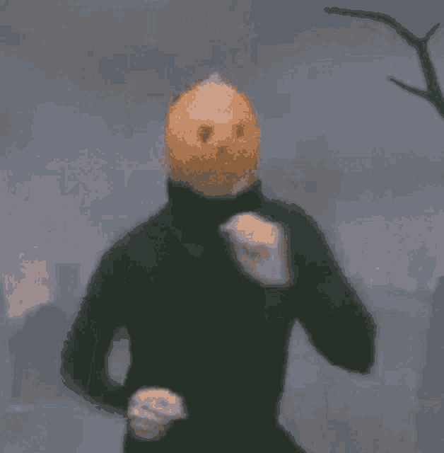a man wearing a pumpkin head is holding a cup of coffee .