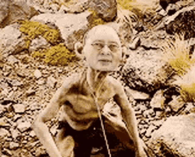 a naked man with glasses and headphones is sitting on a rock .