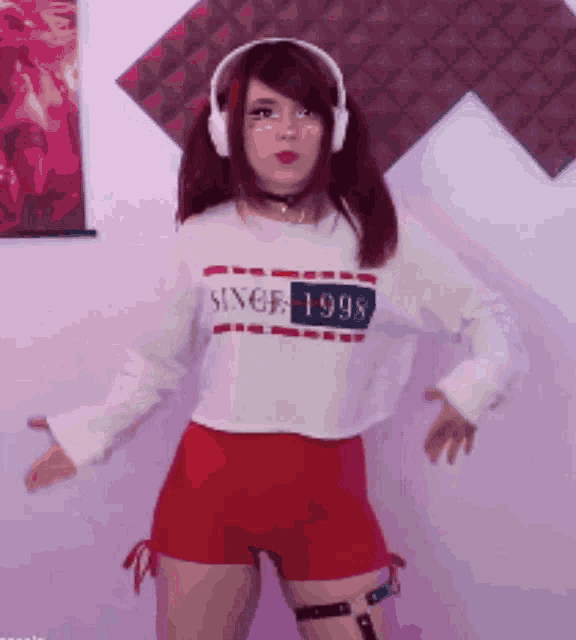 a woman wearing headphones and a crop top that says since 1998
