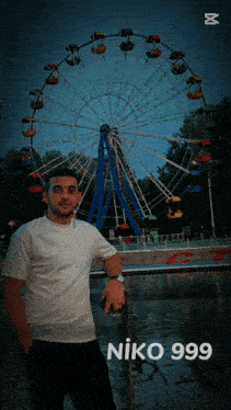a man standing in front of a ferris wheel with niko 999 on the bottom