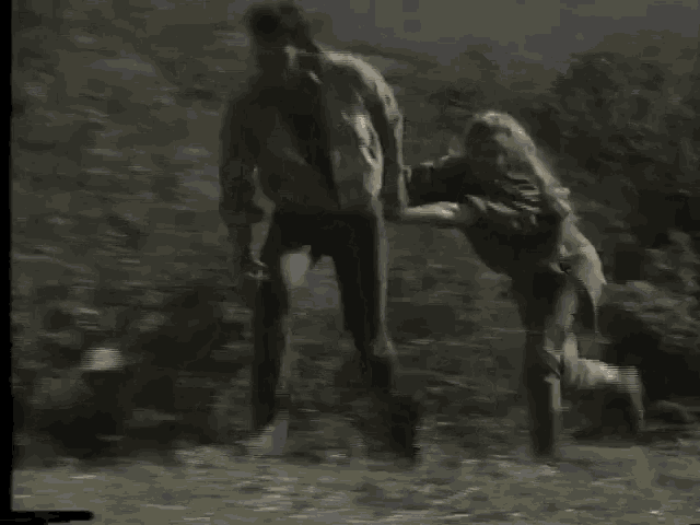 a man and a woman are running through a grassy field .