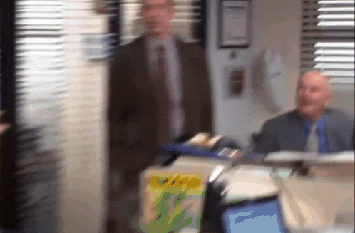 a blurry picture of a man in a suit and tie standing in front of a box of jimmy johns