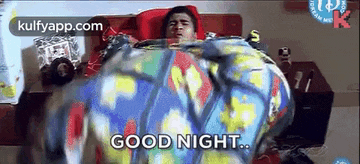 a man is laying on a bed with a colorful blanket and says `` good night '' .