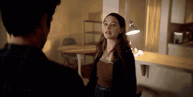 a man and a woman are standing next to each other in a room with a lamp .