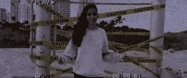 a woman stands in front of a caution tape fence