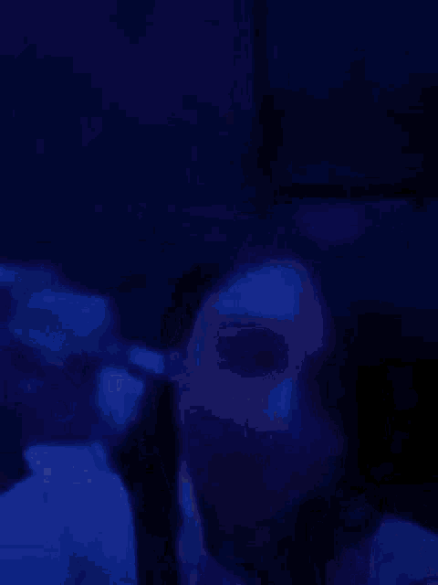 a woman is sitting on a couch with a blue light behind her .