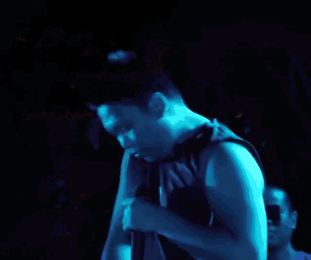 a man in a black tank top and colorful shorts is standing in front of a microphone
