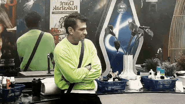 a man in a neon green shirt is standing in front of a mirror .