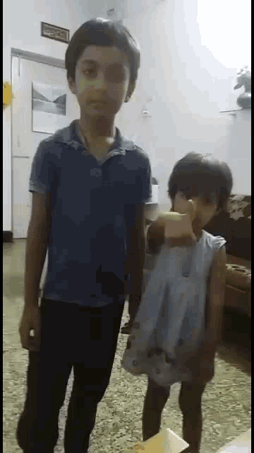 a boy and a girl are standing in a living room .