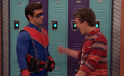 a man in a superhero costume is talking to another man in front of lockers