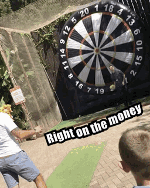 a man throws a dart at a dart board with the words right on the money below him