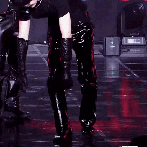 a man in a black shirt and leather gloves is kneeling on a stage