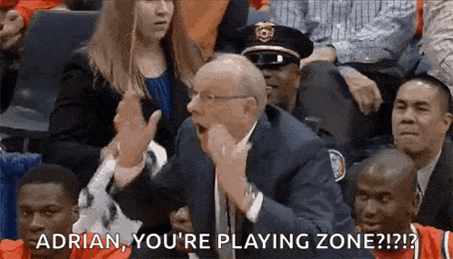 a man in a suit and tie is talking to a basketball player in a crowd .