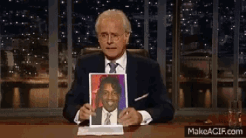 a man in a suit and tie is holding a picture of a man in a suit and tie