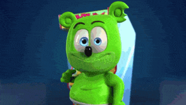 a green gummy bear is standing in front of a machine