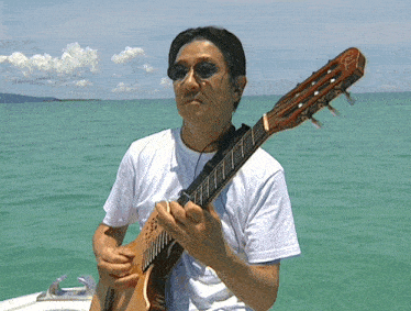 a man in a white shirt is playing a guitar