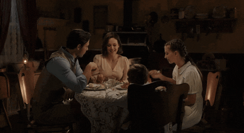 a family is sitting at a table with plates of food