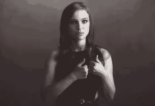 a woman in a black dress is holding her hair