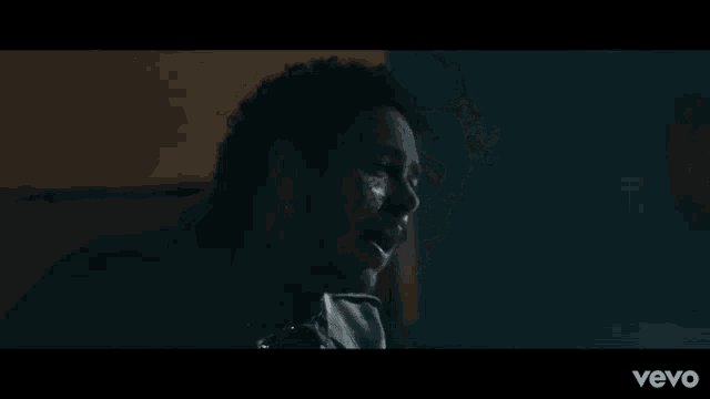 a close up of a man 's face in a dark room in a video .