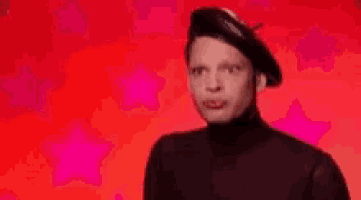 a drag queen wearing a black beret and a black turtleneck is making a funny face .
