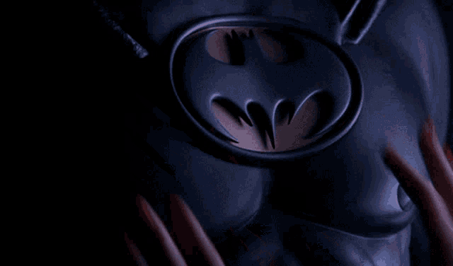 a woman with red nails is touching the chest of a man in a batman costume