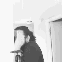 a black and white photo of a person covering their face with their hand .