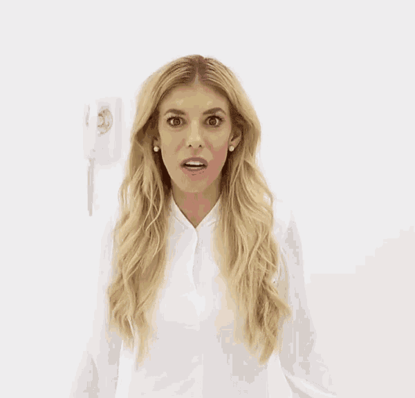 a woman with a surprised look on her face is wearing a white shirt