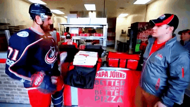 two men standing in front of a papa johns pizza box