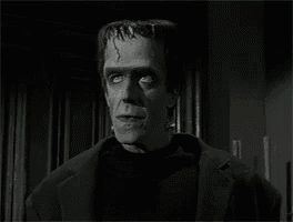 a black and white photo of a man dressed as a monster in a suit .