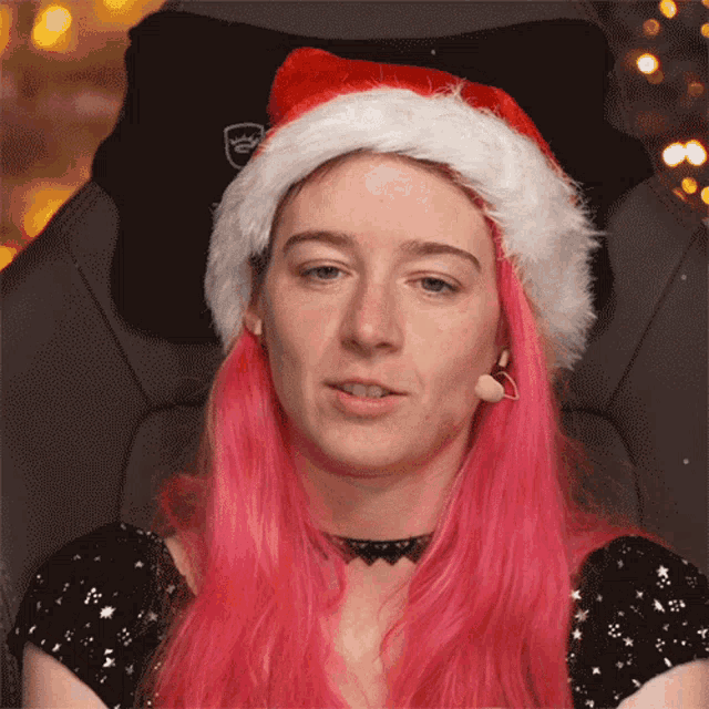 a woman with pink hair and a santa hat on