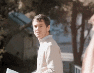 a man in a tan sweater is walking down a sidewalk