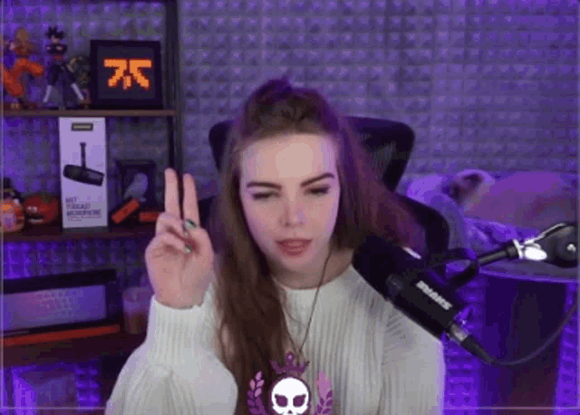 a girl is giving a peace sign in front of a shure microphone .
