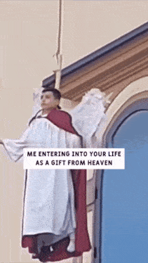 a statue of a priest with angel wings is hanging from a building