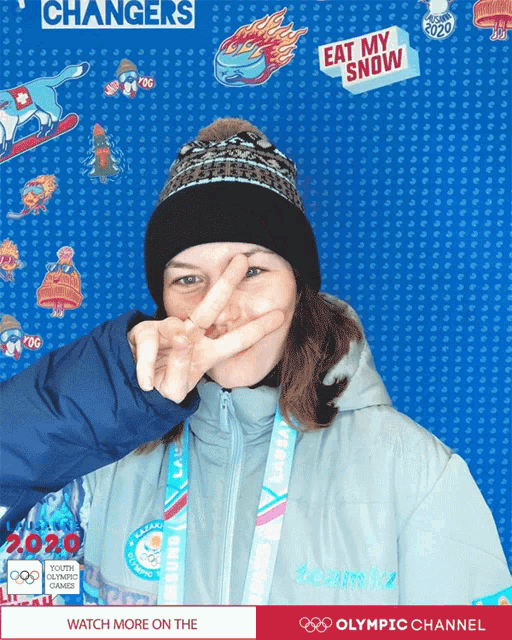 a woman making a peace sign in front of a blue background that says changers
