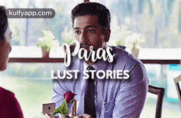 a man in a suit and tie is holding a rose and talking to a woman .