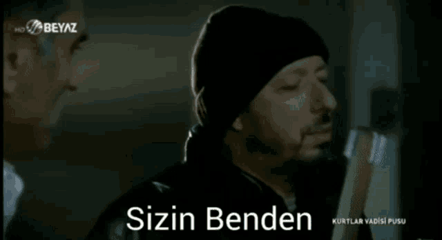 a man in a black hat is talking to another man in a white shirt with the words kurtulusunuzmu var lan on the bottom