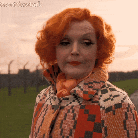 a woman with red hair wearing an orange scarf