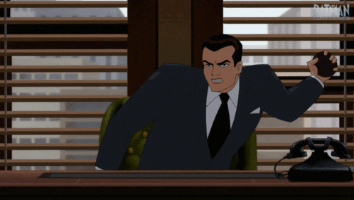 a man in a suit and tie is sitting at a desk with a phone in front of him