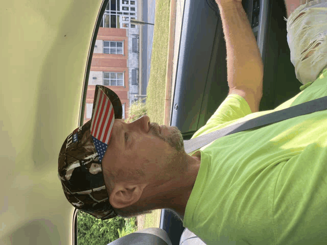 a man wearing a hat with an american flag on it is sitting in the back seat of a car