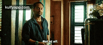 a man is standing in a room holding a cell phone and says not at all .