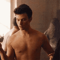 a shirtless man is standing in front of a mirror and looking at himself .
