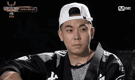 a man wearing a white hat and a black jacket is on a show called show me the money 4 .