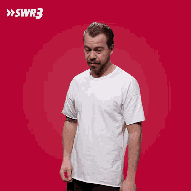 a man in a white shirt is making a face in front of a red background with swr3