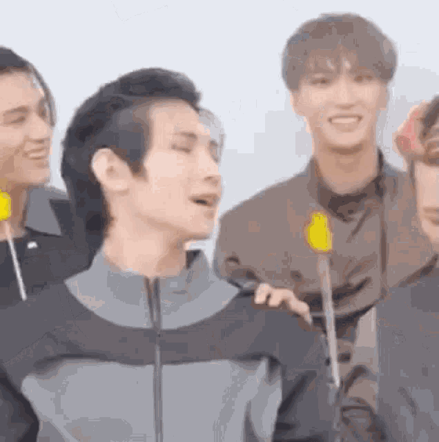 a group of young men are standing next to each other holding lollipops and smiling .