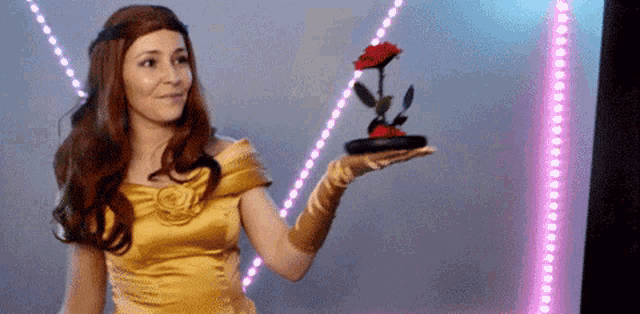 a woman in a yellow dress is holding a red rose