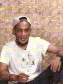 a man wearing a white hat and a white t-shirt smiles for the camera