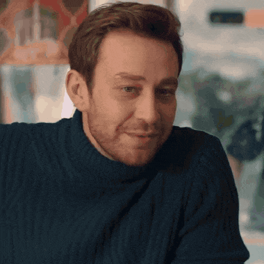 a man wearing a blue sweater is smiling and looking at the camera