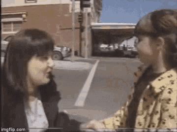 two young girls are standing next to each other on a street corner .