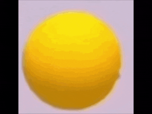 a close up of a yellow ball on a white surface .